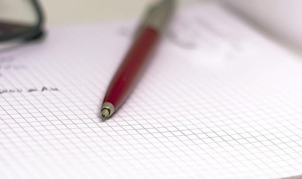 Red pen on an open squared notebook. Business and scheduling concept