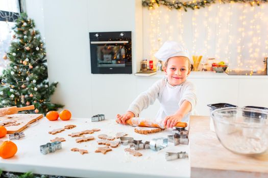 Cute little boy making gingerbread, cutting cookies of gingerbread dough. Christmas bakery. Festive food, cooking process, family culinary, Christmas and New Year traditions concept