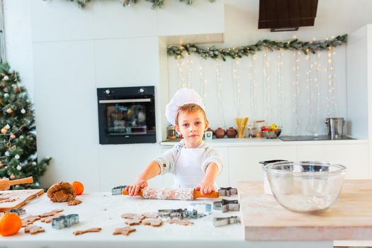 Cute little boy making gingerbread, cutting cookies of gingerbread dough. Christmas bakery. Festive food, cooking process, family culinary, Christmas and New Year traditions concept