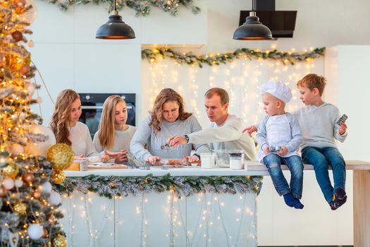 Big happy family making gingerbread, cutting cookies of gingerbread dough, having fun. Festive food, cooking process, family culinary, Christmas and New Year traditions concept. Christmas bakery.