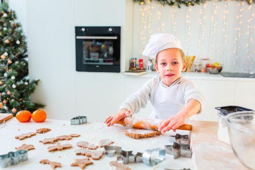 Cute little boy making gingerbread, cutting cookies of gingerbread dough. Christmas bakery. Festive food, cooking process, family culinary, Christmas and New Year traditions concept