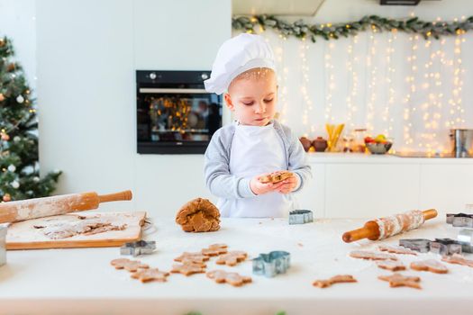 Cute little boy making gingerbread, cutting cookies of gingerbread dough. Christmas bakery. Festive food, cooking process, family culinary, Christmas and New Year traditions concept