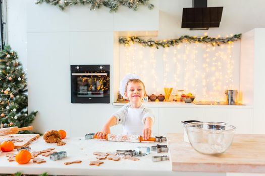 Cute little boy making gingerbread, cutting cookies of gingerbread dough. Christmas bakery. Festive food, cooking process, family culinary, Christmas and New Year traditions concept