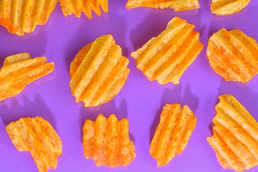 Ribbed potatoes snack with pepper on blue and violet background. Ridged potato chips on blue and violet background. Collection. Flat lay. Close-up.