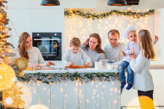 Big happy family making gingerbread, cutting cookies of gingerbread dough, having fun. Festive food, cooking process, family culinary, Christmas and New Year traditions concept. Christmas bakery.