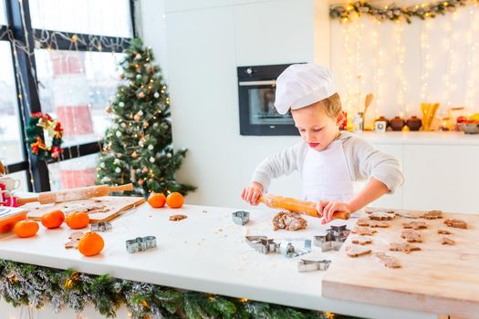 Cute little boy making gingerbread, cutting cookies of gingerbread dough. Christmas bakery. Festive food, cooking process, family culinary, Christmas and New Year traditions concept