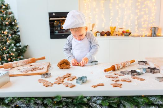 Cute little boy making gingerbread, cutting cookies of gingerbread dough. Christmas bakery. Festive food, cooking process, family culinary, Christmas and New Year traditions concept