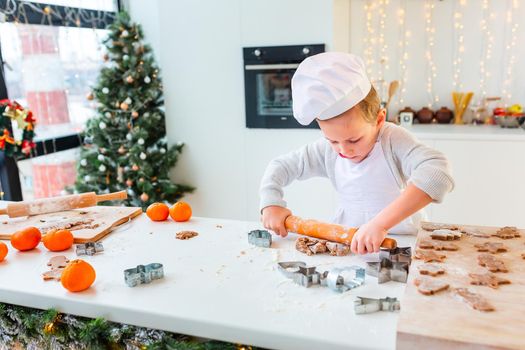 Cute little boy making gingerbread, cutting cookies of gingerbread dough. Christmas bakery. Festive food, cooking process, family culinary, Christmas and New Year traditions concept