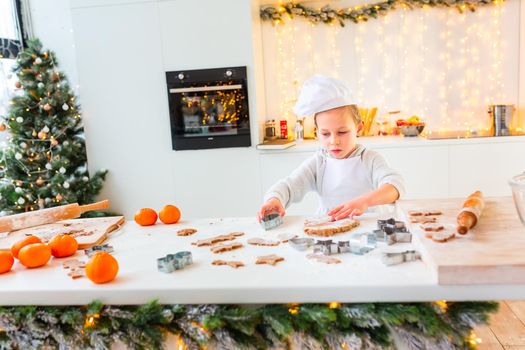 Cute little boy making gingerbread, cutting cookies of gingerbread dough. Christmas bakery. Festive food, cooking process, family culinary, Christmas and New Year traditions concept