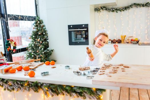 Cute little boy making gingerbread, cutting cookies of gingerbread dough. Christmas bakery. Festive food, cooking process, family culinary, Christmas and New Year traditions concept