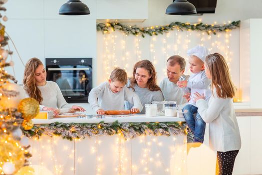 Big happy family making gingerbread, cutting cookies of gingerbread dough, having fun. Festive food, cooking process, family culinary, Christmas and New Year traditions concept. Christmas bakery.