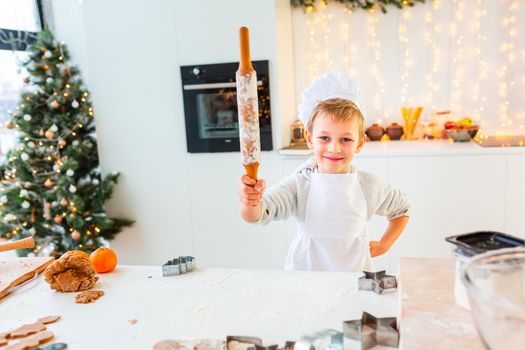 Cute little boy making gingerbread, cutting cookies of gingerbread dough. Christmas bakery. Festive food, cooking process, family culinary, Christmas and New Year traditions concept