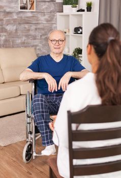 Nurse consulting an old man in wheelchair sitting in the living room. Disabled disability old person with medical worker in nursing care home assistance, healthcare and medicine service