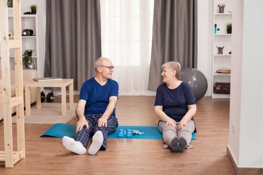 Old couple having fun doing sport in living room. Old person healthy lifestyle exercise at home, workout and training, sport activity at home on yoga mat.