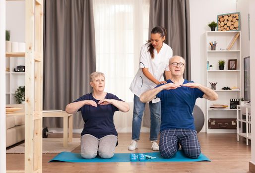 Senior couple doing physical therapy with doctor at home. Home assistance, physiotherapy, healthy lifestyle for old person, training and healthy lifestyle