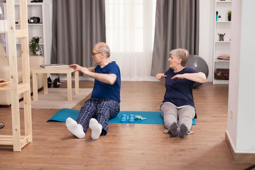 Retirees doing sports together at home. Old person healthy lifestyle exercise at home, workout and training, sport activity at home on yoga mat.