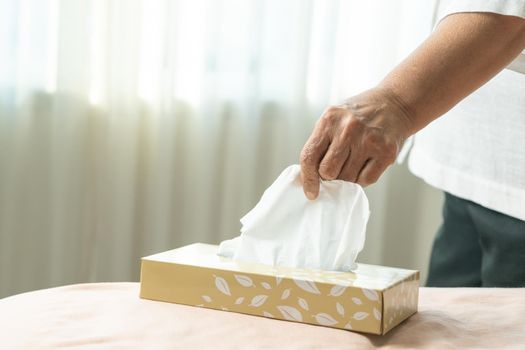Senior women hand picking napkin/tissue paper from the tissue box