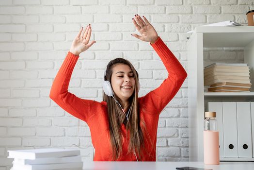 Social media. Young caucasian woman wearing earphones dancing sitting at the table