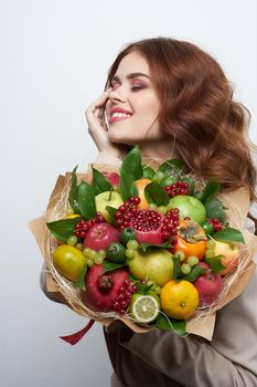 portrait of a woman fun posing fruit bouquet vitamins light background. High quality photo