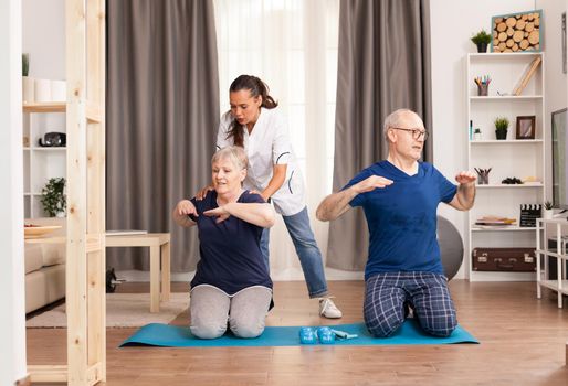 Nurse doing physical therapy with senior couple. Home assistance, physiotherapy, healthy lifestyle for old person, training and healthy lifestyle