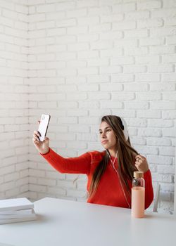 Social media. Young caucasian woman listening to the music taking selfie