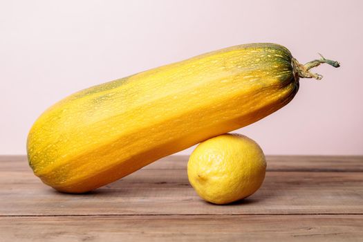 Yellow ripe zucchini with lemon on wooden boards. Autumn concept. Close-up.