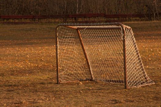 Old iron rusty football goal for mini football on trampled lawn in forest zone of city park.