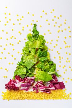 Christmas tree made from green salad products, cabbage, raw pasta. View from above