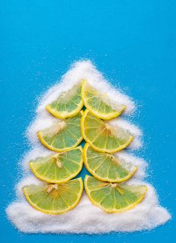 Christmas tree made from lemon and sugar fruits on a blue background.