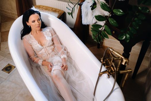 the bride, dressed in a boudoir transparent dress and underwear, lies in a vintage bathroom. Morning of the bride.
