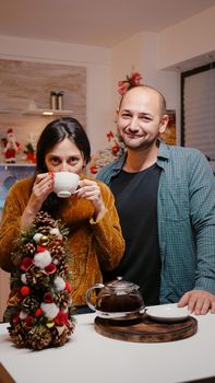 Couple using video call communication on christmas eve, talking to family and friends from decorated home. Man and woman chatting on online conference, celebrating holiday on internet.