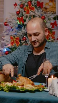 Couple eating chicken at festive dinner on christmas eve celebrating with traditional food and glasses on champagne at home. Man and woman enjoying holiday festivity with food and alcohol
