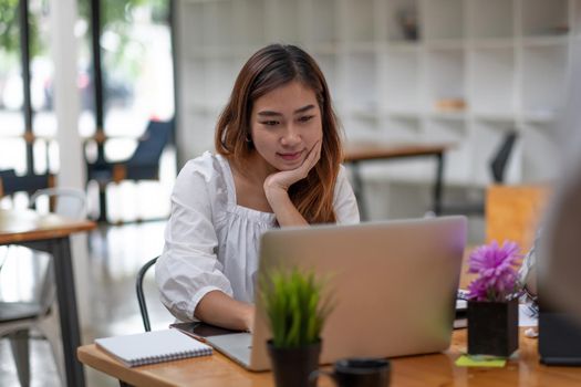 Happy asian woman using laptop computer at cafe coffee shop.