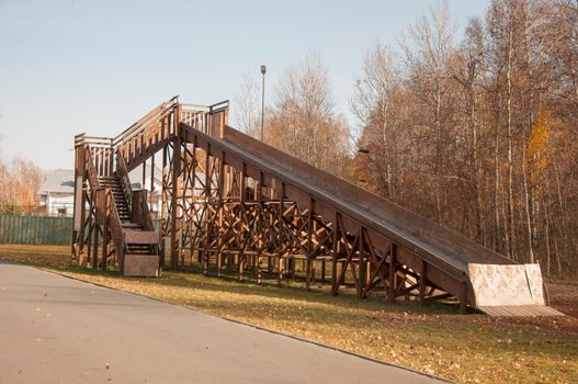 A large wooden slide for sleds. Empty inactive in the autumn