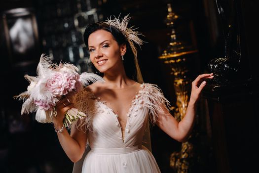 The bride in a wedding dress and with a bouquet stands at the old interior of the castle.