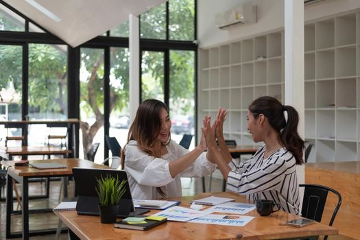 Two happy friendly business people giving high five in office celebrating success, good cooperation result, partnership teamwork and team motivation in office work.