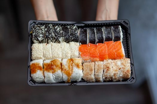 Making sushi and rolls at home. Sushi with seafood, salad and white rice. Food for family and friends. A set of different rolls and sushi on a tray.