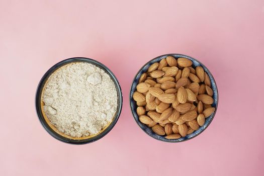 almond powder and almond in a bowl on pink .