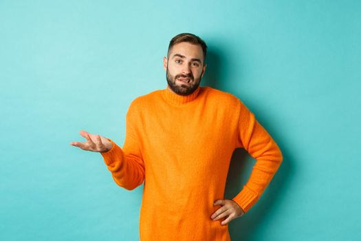 Careless and indifferent guy shrugging, looking unbothered, dont know anything, standing over light blue background.