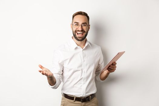 Satisfied businessman praising good work, reading report on digital tablet, standing happy against white background.