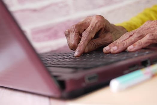 senior women's hand typing on laptop