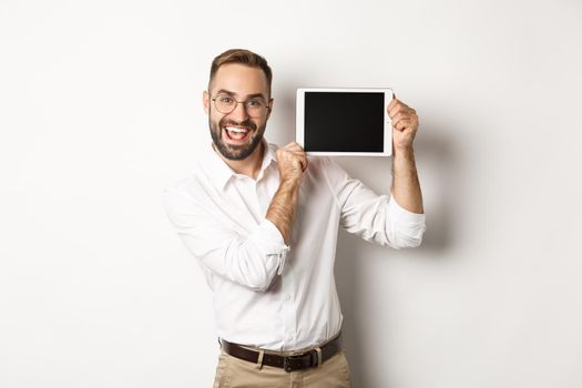 Shopping and technology. Handsome man showing digital tablet screen, wearing glasses with white collar shirt, studio background.