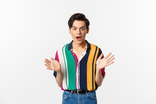 Excited and amazed handsome guy raise hands and looking at camera with temptation, wanting something, standing over white background.