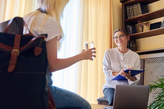 Woman psychologist working with teen girl in office. Visit and counseling of professional mental and social therapist. Psychology, teenager, problem, trauma, mental health of adolescents concept