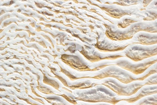 White-beige texture of Pamukkale calcium travertine in Turkey, uneven pattern, close-up