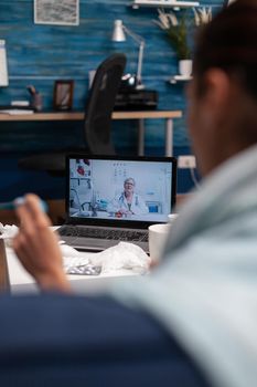 Woman on computer webcam consultation with doctor sitting at home. Young patient with cold flu illness fever temperature virus calling for support medicine diagnostic and medications