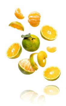 Fresh ripe green mandarine with leaf falling in air. Cut, peeled, slices and whole green tangerine isolated on white background with clipping path. Food levitation concept
