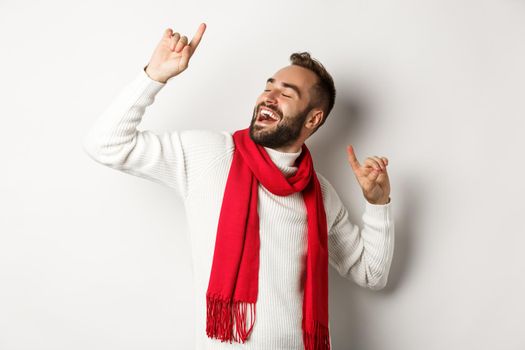 Happy man celebrating christmas party, dancing and pointing fingers, standing over white background.