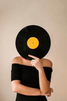 young woman holding vinyl record her face. High resolution photo