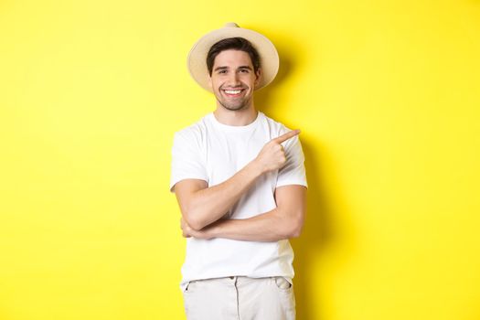 Young male tourist pointing finger right, smiling and showing advertisement, concept of tourism and lifestyle, yellow background.